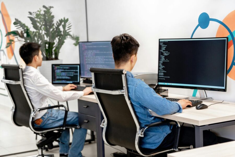 two folks working on a computer checking code and testing