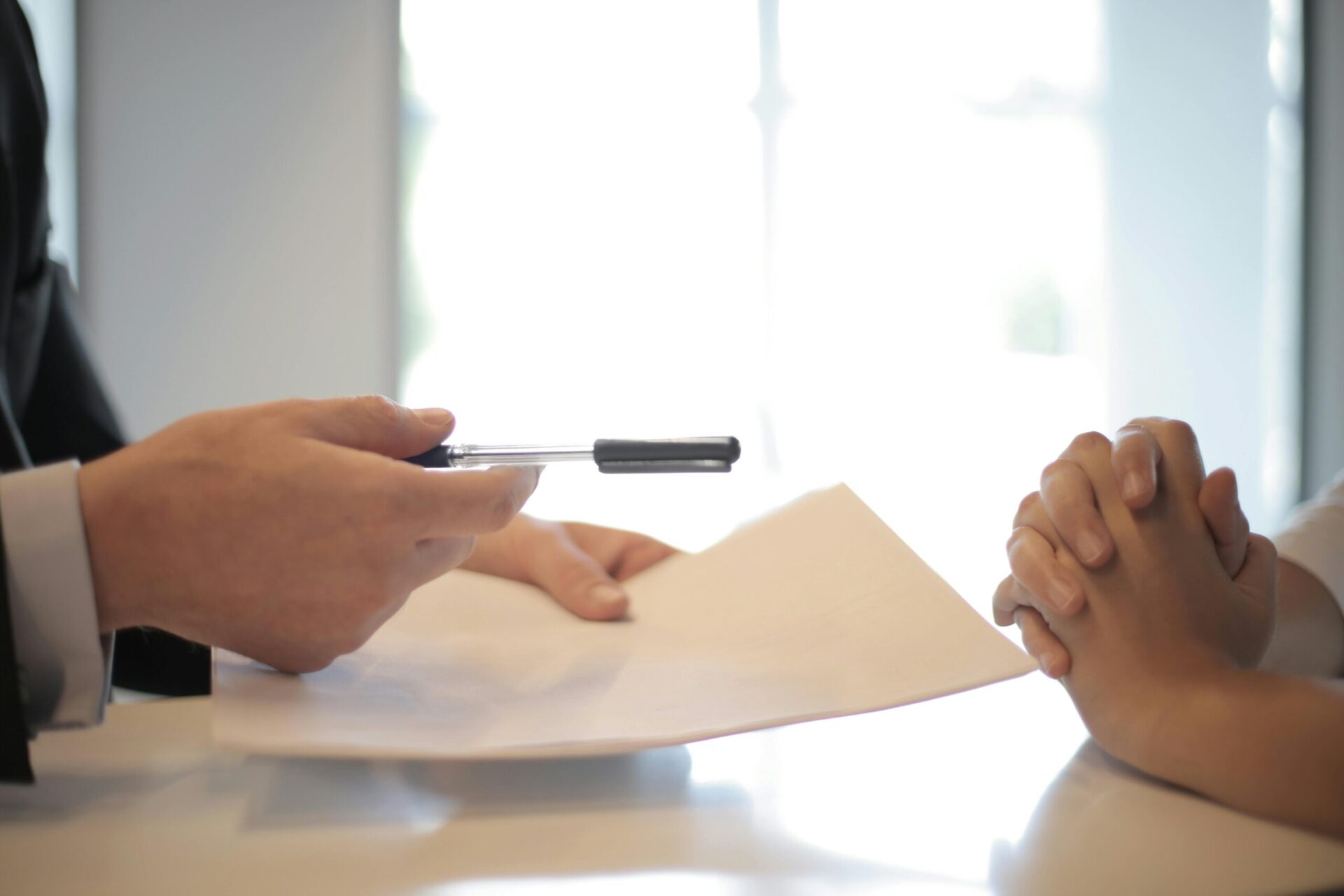 person offering pen and paper to another