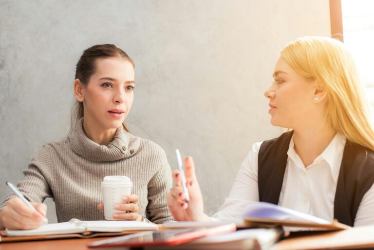 two woman executives in a discussion with book and coffee